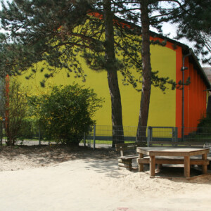 Der Außenbereich unserer OGS: Eine großzügiger Sandkasten und eine gemütliche Sitzmöglichkeit.